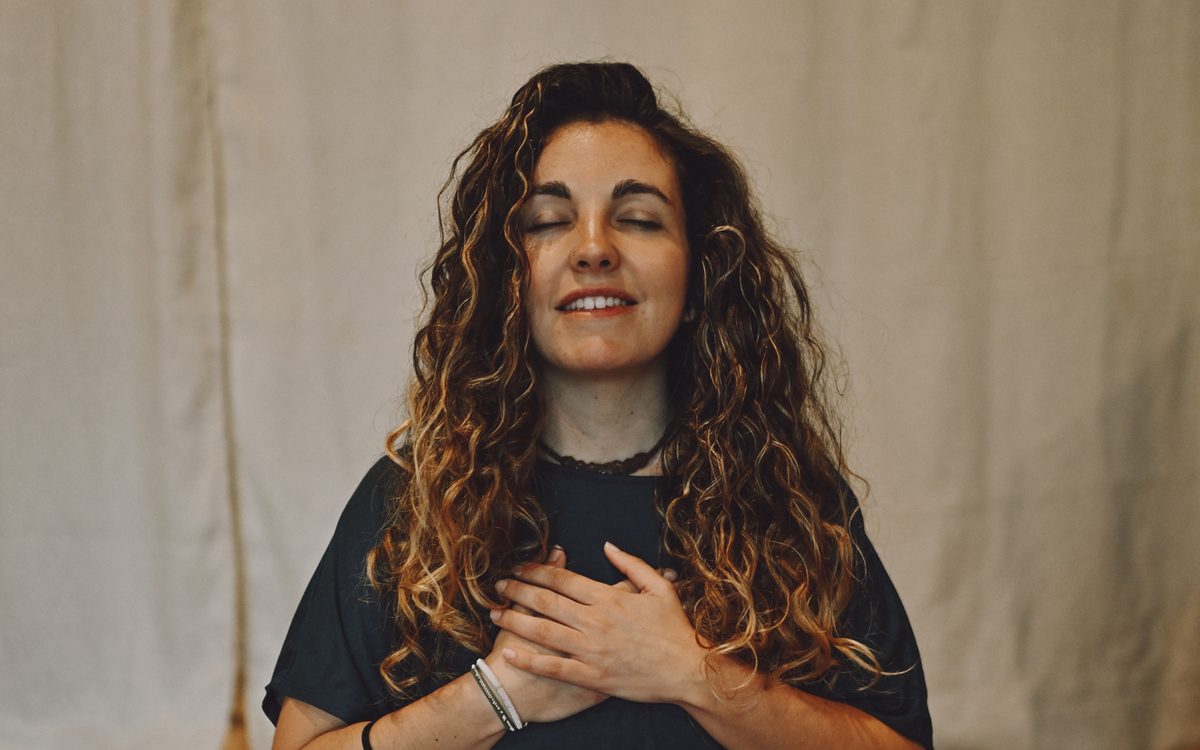 Persona sentada con los ojos cerrados y una mano en el pecho, escuchando en calma.